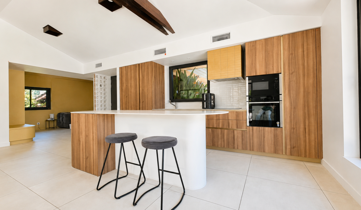 Rénovation de cuisine ouverte sur-mesure à Valras-Plage avec îlot central aux lignes courbes, façades en bois chaleureux et électroménager encastré par Sophie Pico