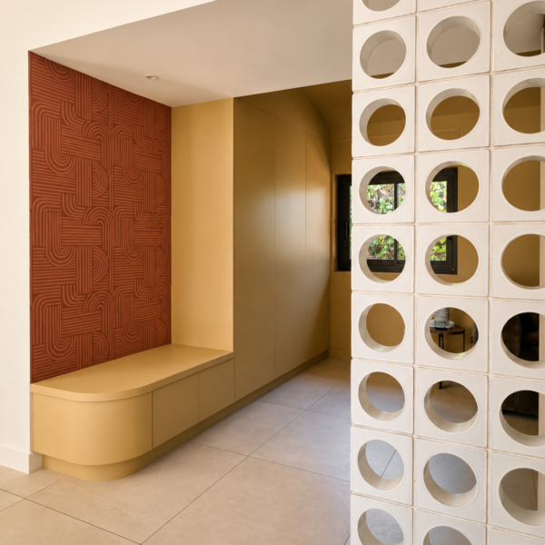Claustra blanc en blocs perforés filtrant la lumière devant le meuble d'entrée sur-mesure avec banquette et papier peint terracotta à Valras-Plage par Sophie Pico