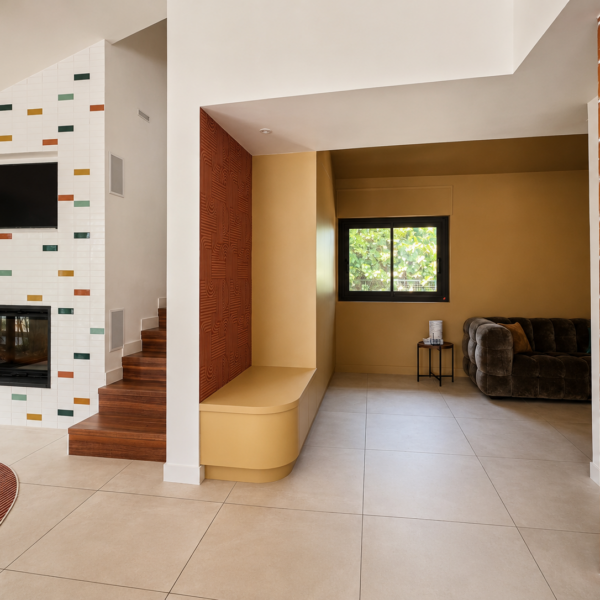 Perspective architecturale d'un salon rénové à Valras-Plage avec cheminée à cabochons, banquette maçonnée ocre, claustra en terre cuite et escalier en bois par Sophie Pico