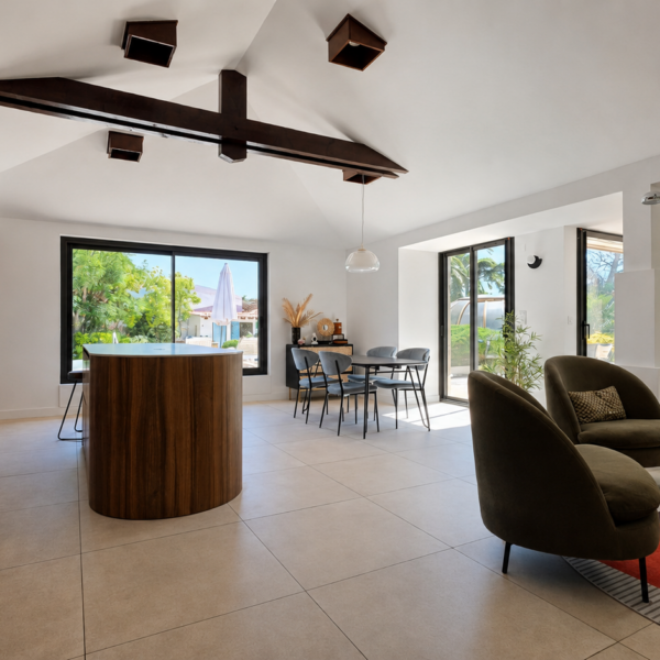 Vue très large de la pièce de vie ouverte sous plafond cathédrale avec cuisine en bois, îlot arrondi, espace repas et coin salon lumineux à Valras-Plage par Sophie Pico