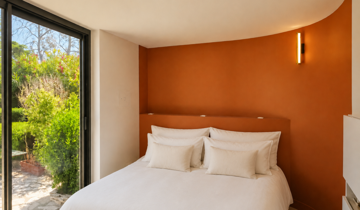 Chambre parentale moderne avec tête de lit sur mesure terracotta et mur arrondi baigné de lumière naturelle
